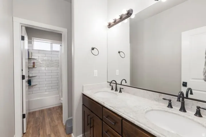 Dual vanity with light-toned countertop, dark wood-finish cabinetry, and matte black hardware