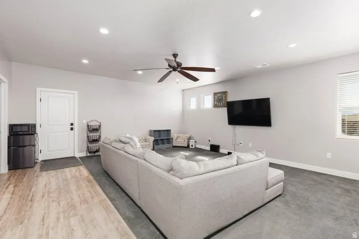 Recessed lighting, ceiling fan, wood-finish flooring, white paneled door, and multiple windows