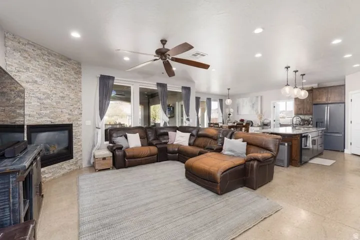 Stone-clad fireplace feature wall, recessed lighting, and a ceiling fan