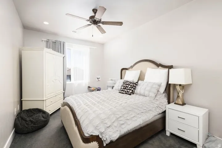 Tray ceiling with a ceiling fan, recessed lighting, and a window with curtain rod