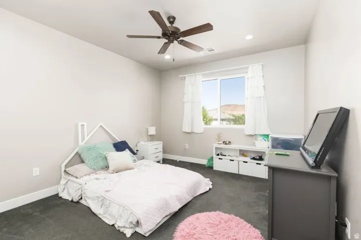 Recessed lighting, ceiling fan with dark wood-finish blades, white window frames, dark gray carpeting, and light gray wall paint