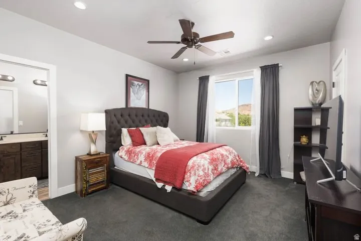 Recessed lighting, ceiling fan, carpet flooring, a window, and a dark wood-finish vanity with dual sinks
