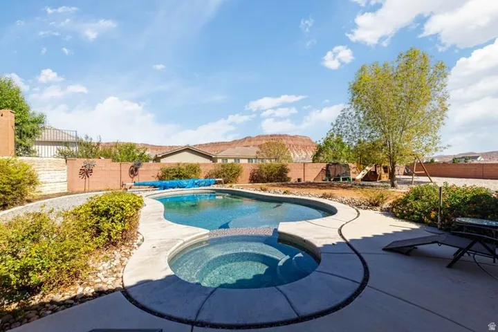 Outdoor pool with integrated spa and surrounding concrete patio