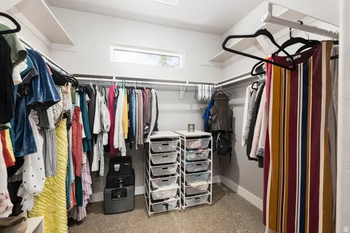 Spacious closet featuring built-in shelving, hanging rods, and a high window