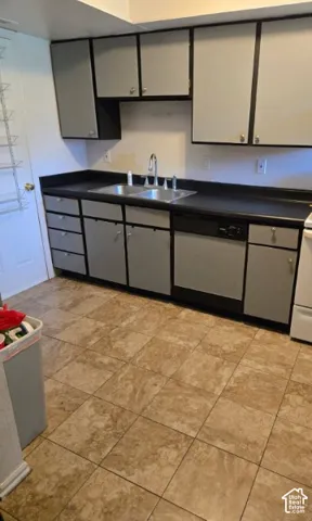 Kitchen featuring gray cabinetry, a double basin stainless steel sink, black countertops, and a built-in dishwasher