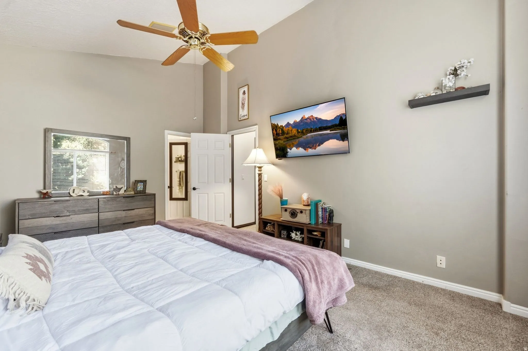 Vaulted ceiling with a ceiling fan, neutral wall paint, and gray carpet