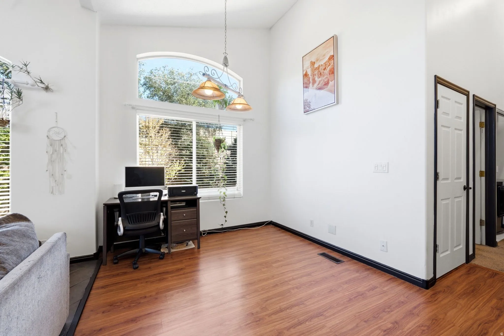 Vaulted ceiling, arched transom window, wood-finish flooring, white walls, and built-in doors