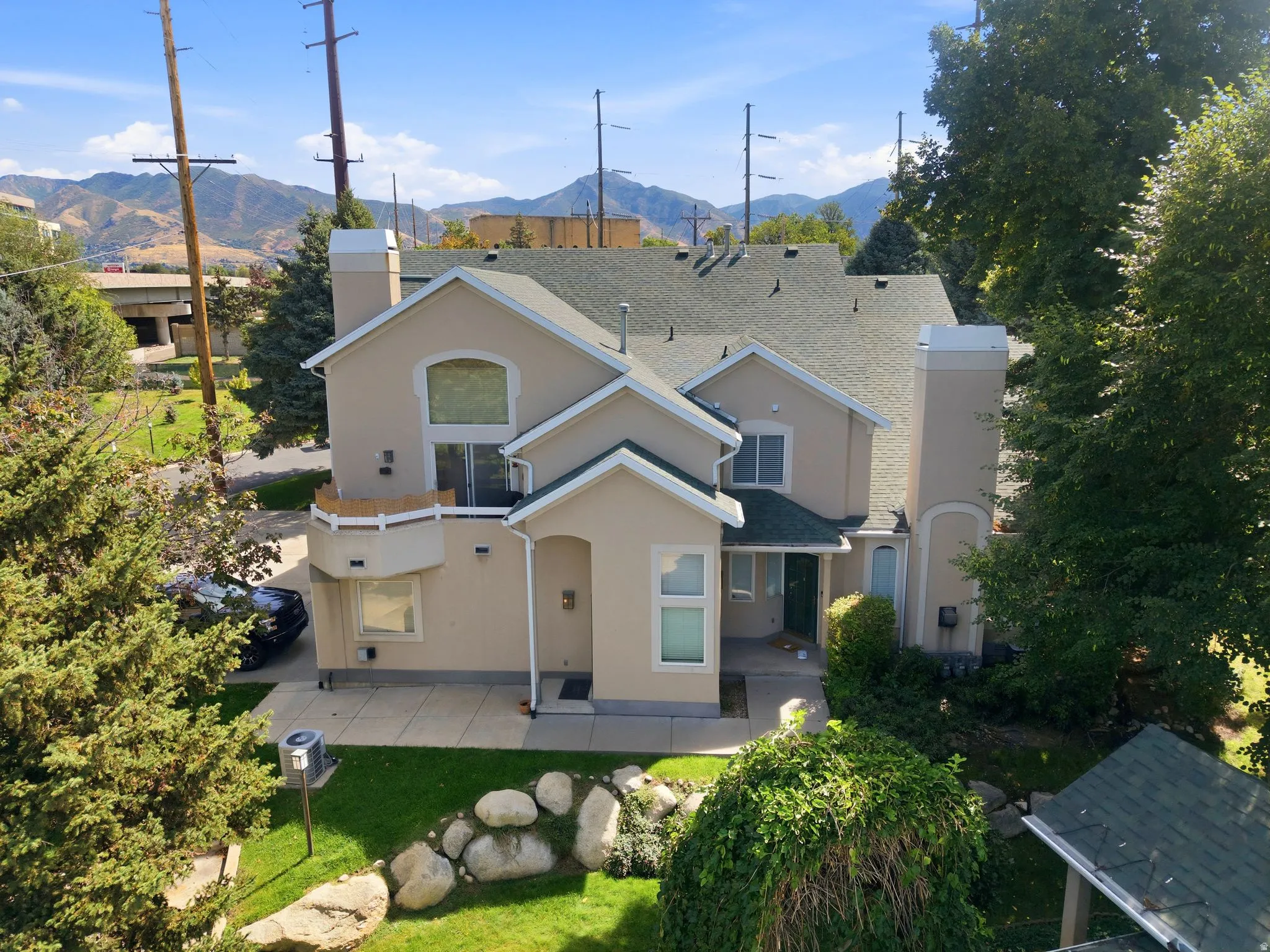 Stucco exterior with multiple windows, prominent chimneys, and an attached balcony