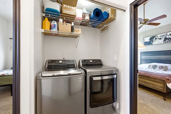 Laundry closet featuring a built-in wire shelving system, a front-loading washing machine, and a front-loading dryer