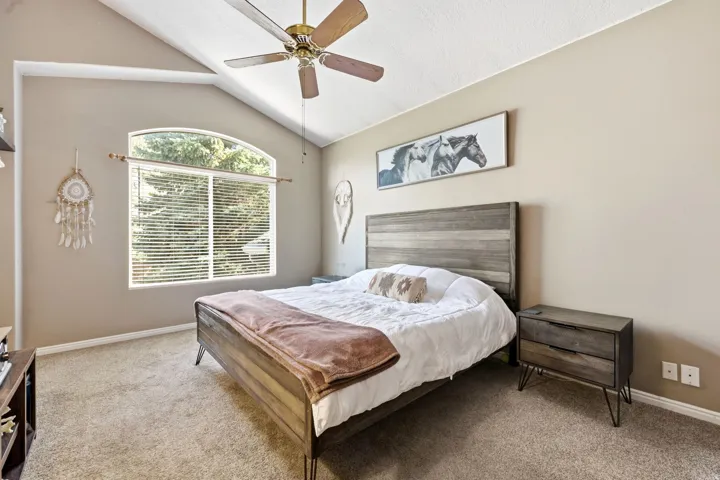 Vaulted ceiling with ceiling fan, arched window with horizontal blinds, neutral wall paint, and carpeted flooring