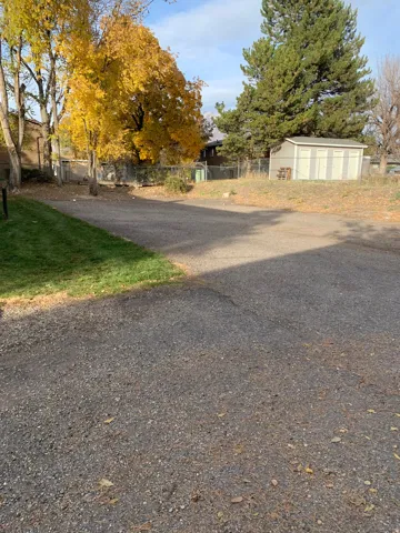 Gravel driveway with a green lawn border and a storage shed
