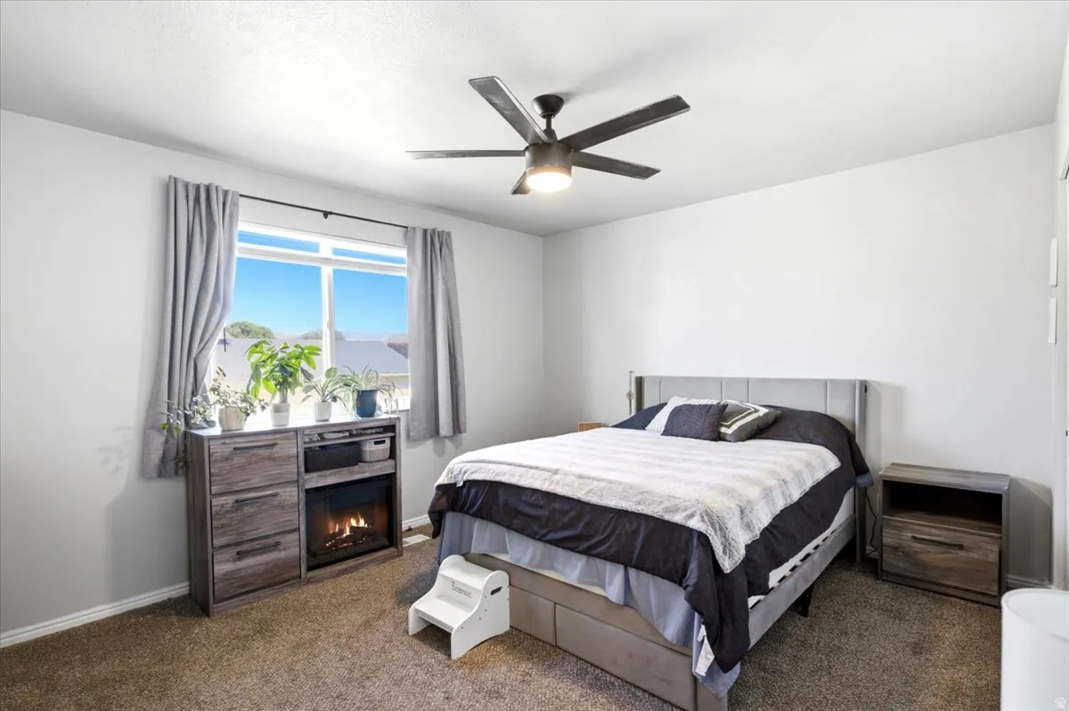 White painted walls, window with natural light, integrated ceiling fan with light, and carpeted flooring