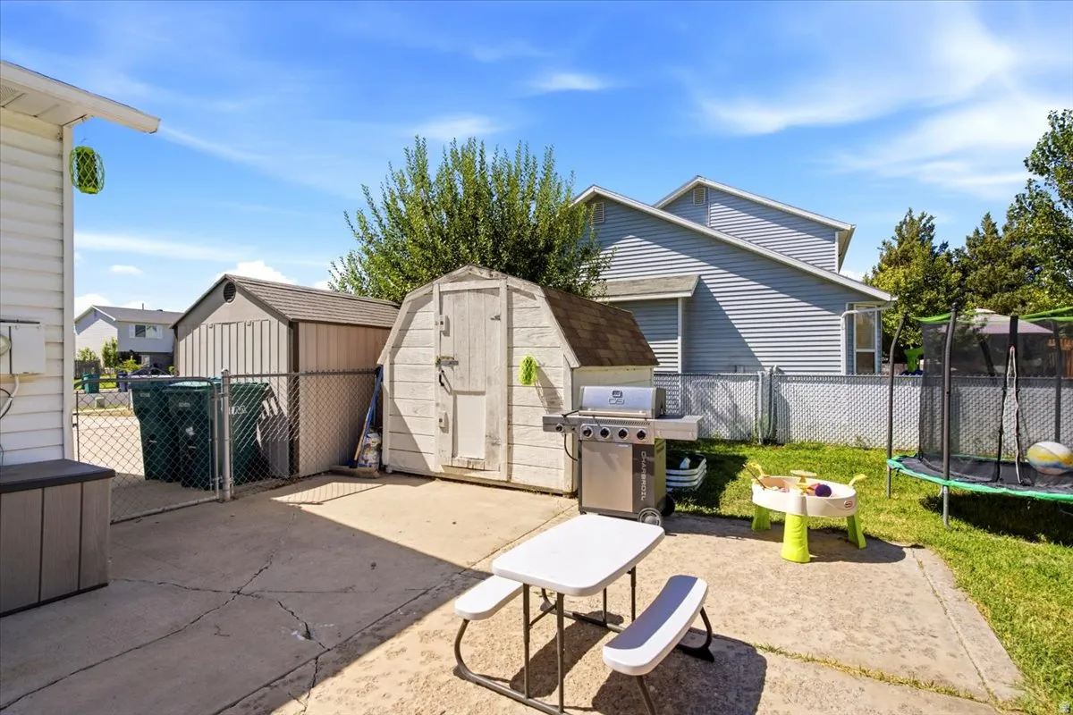 Concrete patio area with two storage sheds and chain link fencing