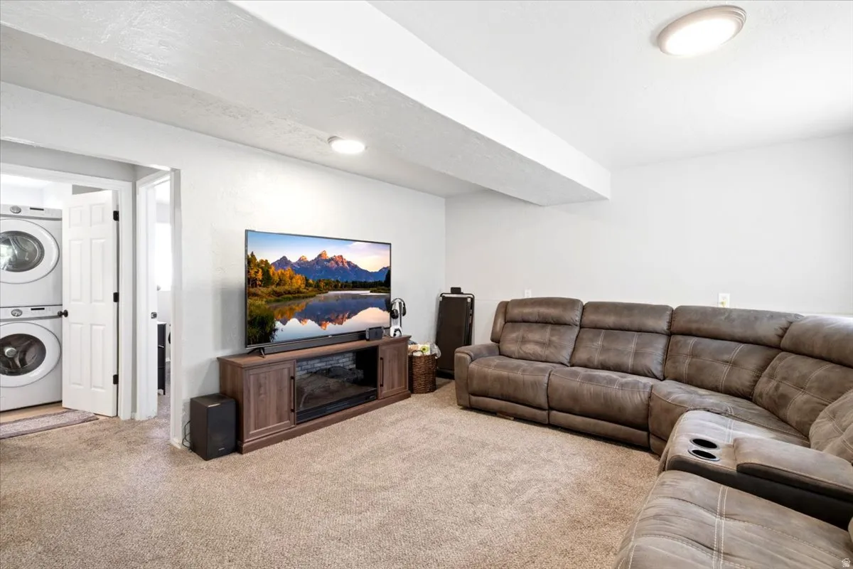 Carpeted room featuring a ceiling-mounted light fixture, white walls, and a wood-finish media console