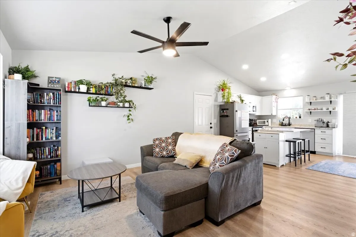 Vaulted ceilings, wood-finish flooring, recessed lighting, ceiling fan, and white cabinetry