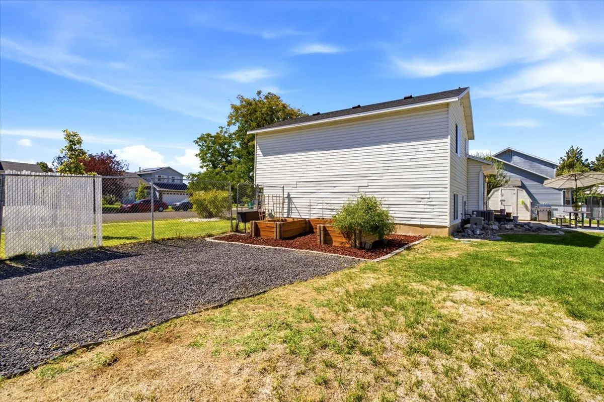 Chain link fencing, gravel ground cover, raised garden beds, and manicured lawn