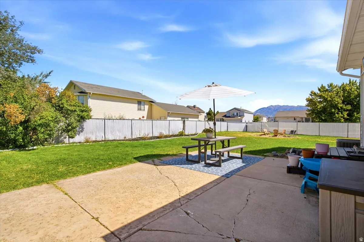 Expansive backyard featuring a concrete patio, a privacy fence, and a large lawn area