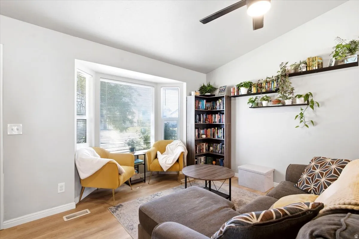 Bay windows with natural light, wood-finish flooring, ceiling fan, and built-in shelving