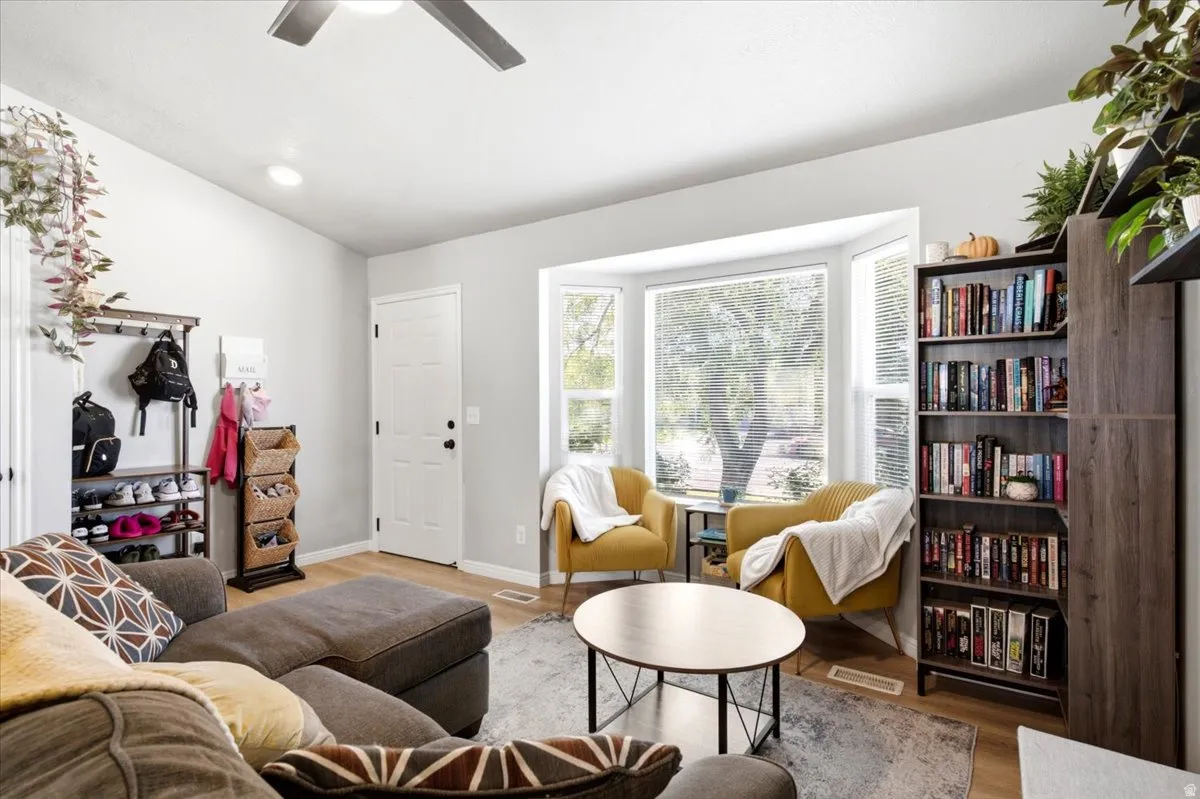 Recessed ceiling lighting, bay window, wood-finish flooring, and ceiling fan