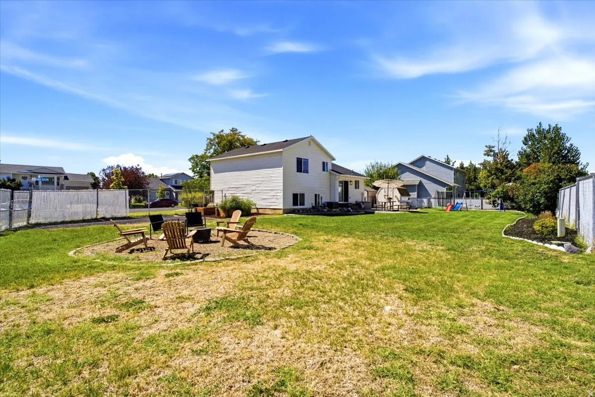 Expansive backyard featuring a large grass area, defined landscaping beds, and a designated fire pit area