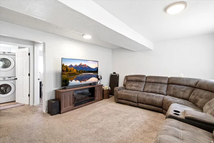 Carpeted room featuring a ceiling-mounted light fixture, white walls, and a wood-finish media console