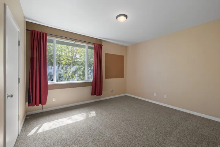 Wall-to-wall carpeting, neutral wall finishes, and a large window
