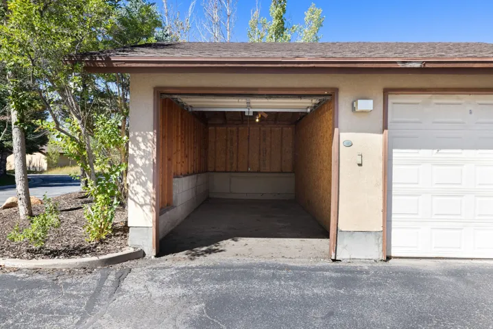 Attached garage featuring a concrete floor, wood-paneled walls, and an overhead light fixture