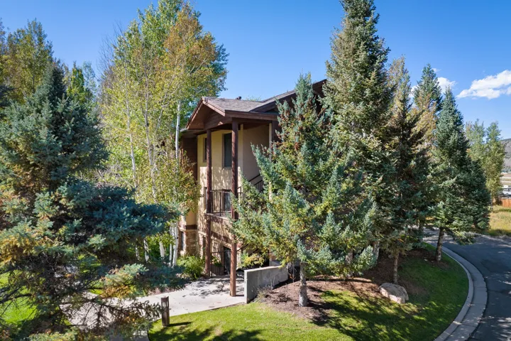 Multi-level residence featuring a stucco and stone exterior, a covered entryway, and a private balcony
