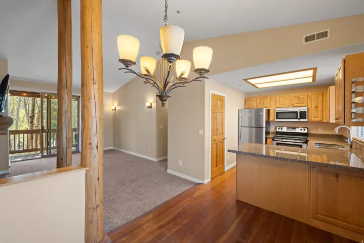 Kitchen with stainless steel appliances, wood cabinetry, and a stone-finish countertop