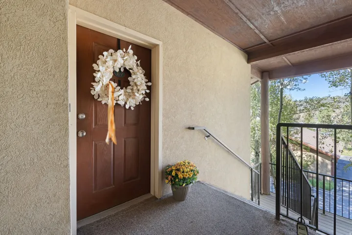 Textured exterior wall, covered entry, and wood-finish door with contrasting trim