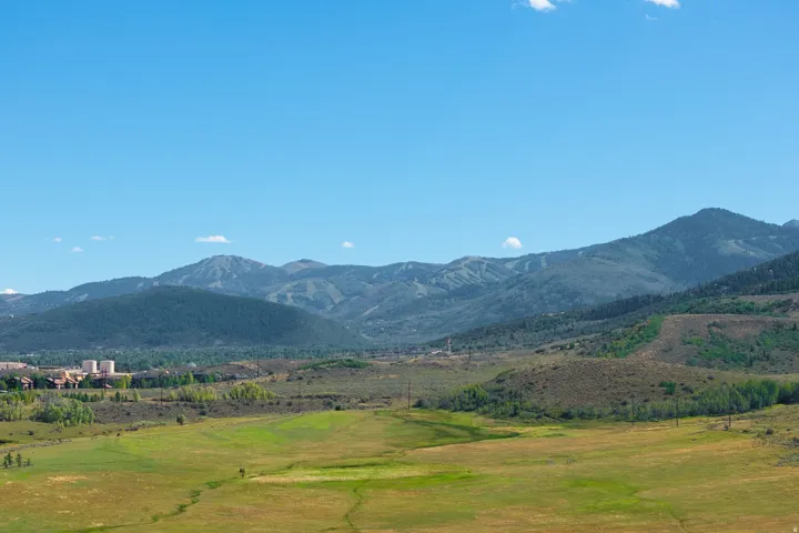 Expansive green and golden fields with distant mountain ranges