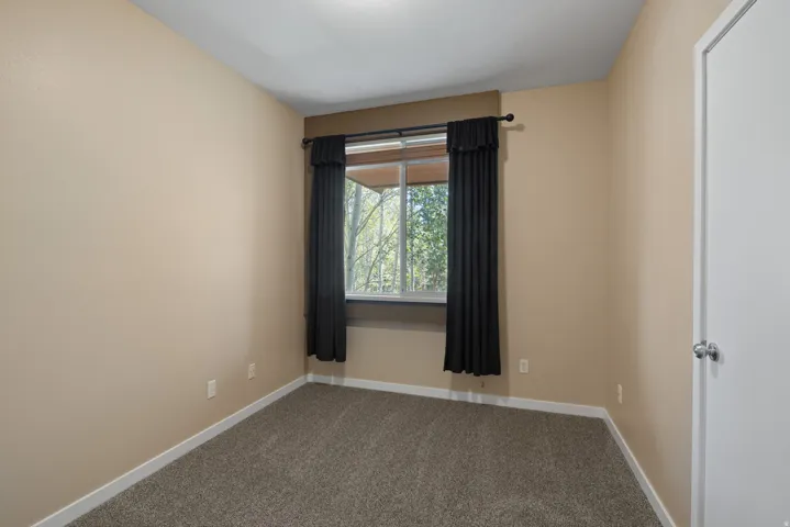 Carpeted flooring, neutral wall tones, and a window with a dark frame