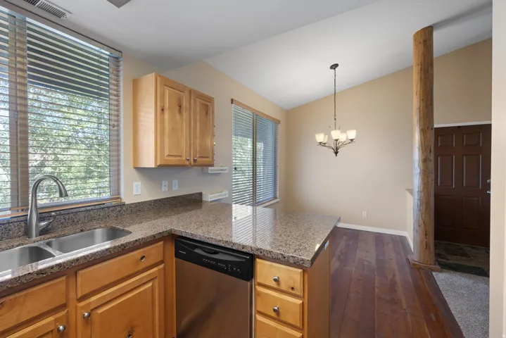 Kitchen featuring wood cabinetry, a double basin stainless steel sink, and speckled countertops