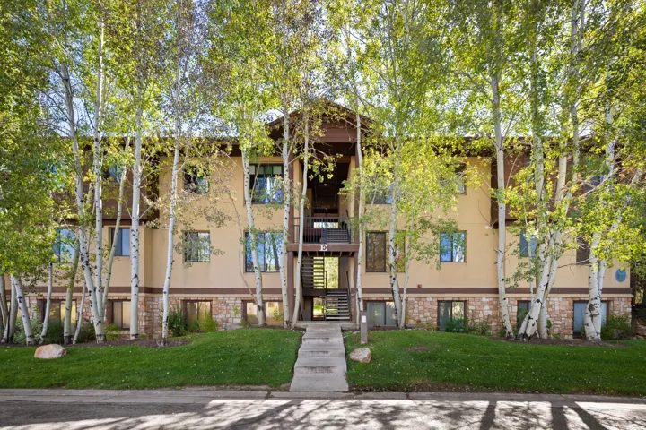 Multi-level building with a stone and stucco facade, complemented by mature deciduous trees