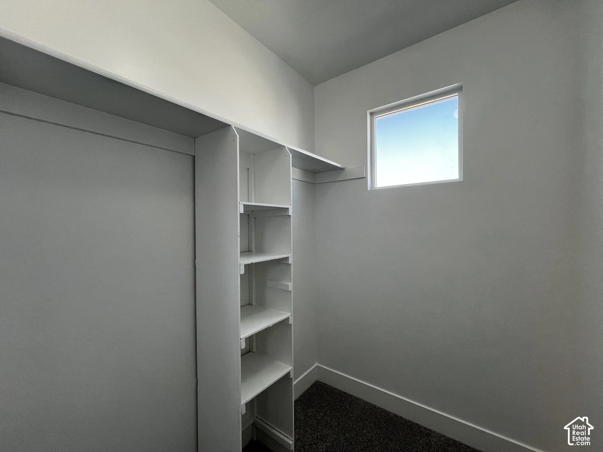 Built-in shelving, white walls, and a single window with white trim