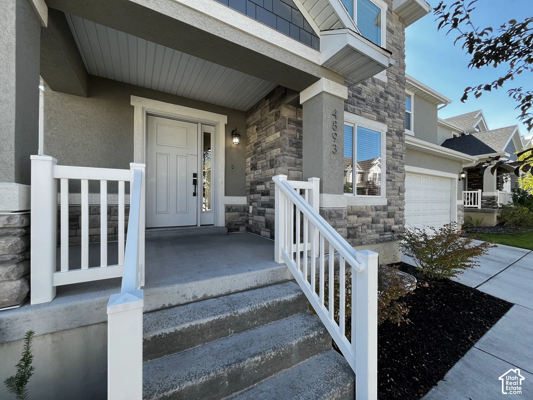 Multi-level facade featuring stone and stucco accents, a covered entry, and white exterior railings