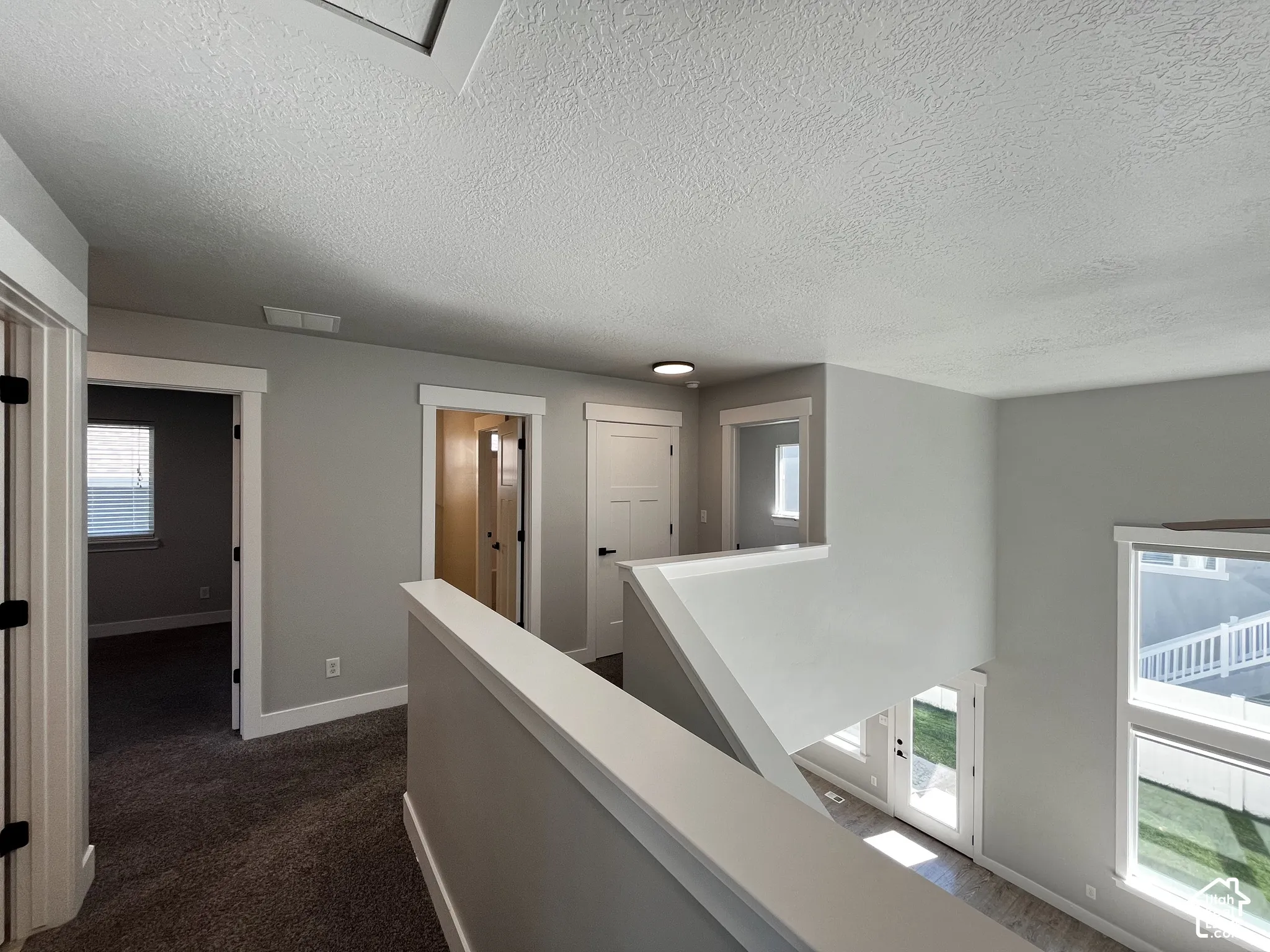 Upper-level landing with carpeted flooring, white trim, and multiple doorways