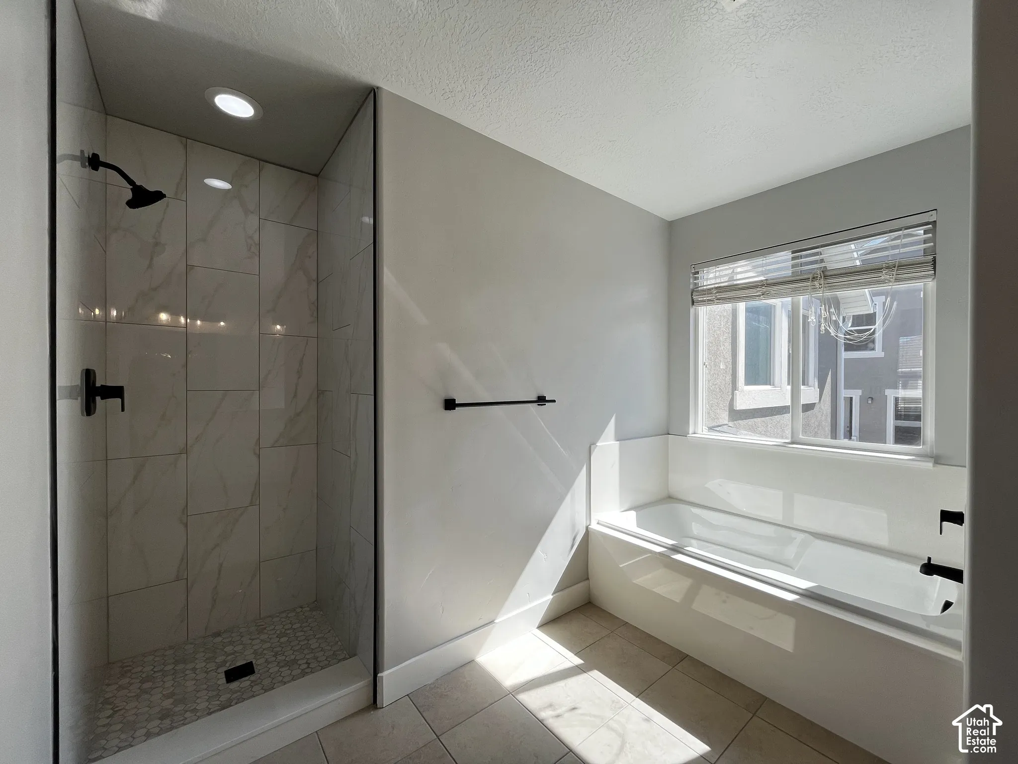 Walk-in shower with clear glass enclosure and contrasting dark fixtures
