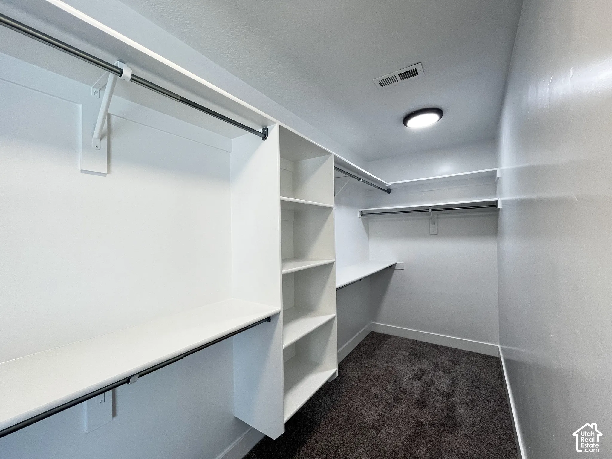 Custom closet shelving with multiple hanging rods, built-in shelves, and a flush-mount ceiling light