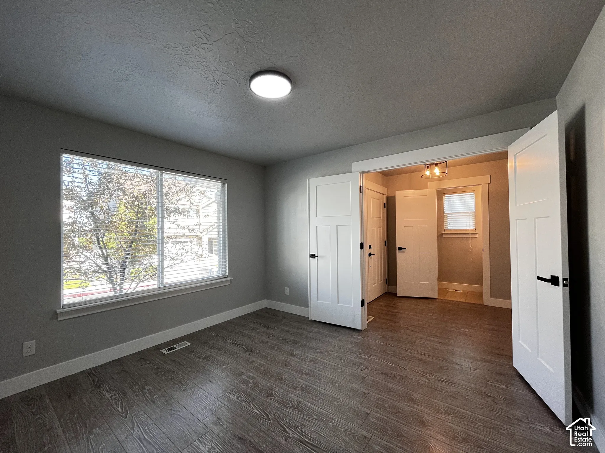 Wood-finish flooring with a neutral wall color, modern flush mount lighting, and white trim