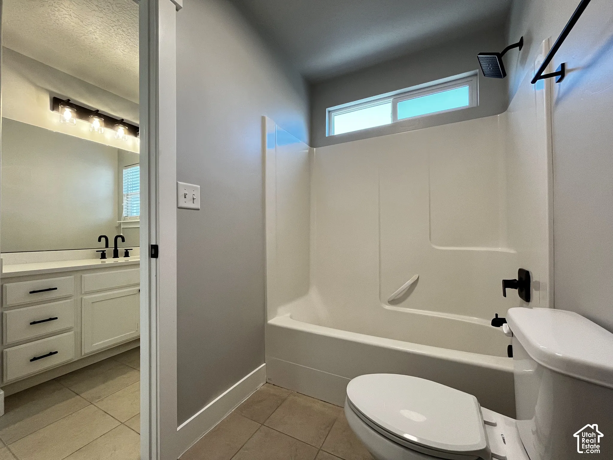 Bathroom featuring a white tub/shower combination, transom window, and matte black fixtures