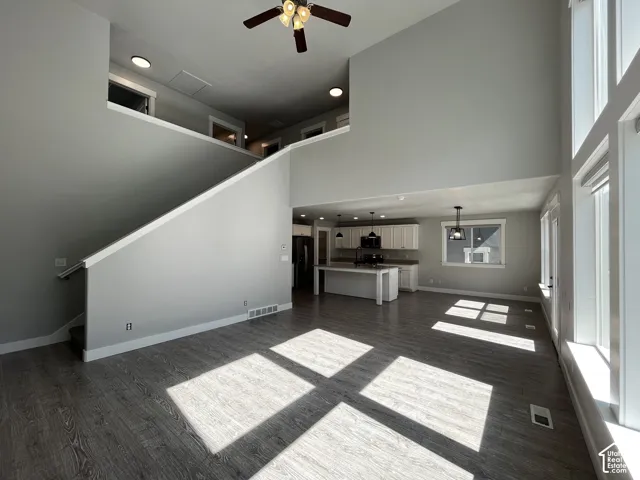 Two-story living space featuring wood-finish flooring, a contemporary ceiling fan, and abundant natural light