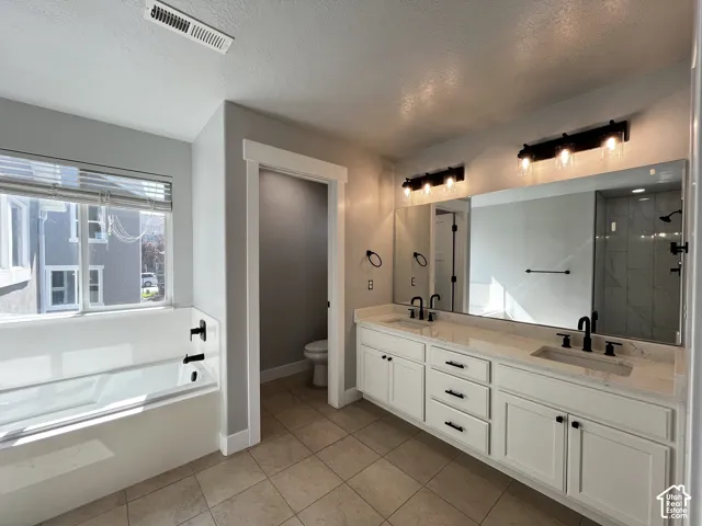 Double vanity with dual sinks, white cabinetry, and stone countertops