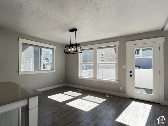 Wood-finish flooring with a contemporary black metal chandelier and multiple windows