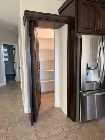 Pantry with multiple built-in shelves, dark wood-finish trim, and tile flooring