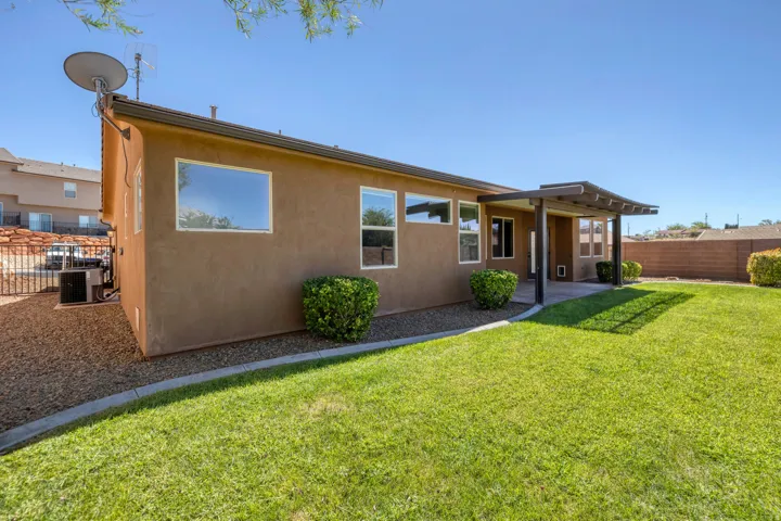 Expansive backyard featuring a manicured lawn, a covered patio, and mature landscaping