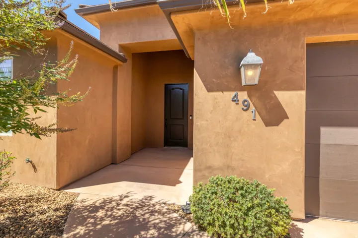 Stucco exterior with a covered entry, dark wood-finish garage door, and a decorative exterior light fixture