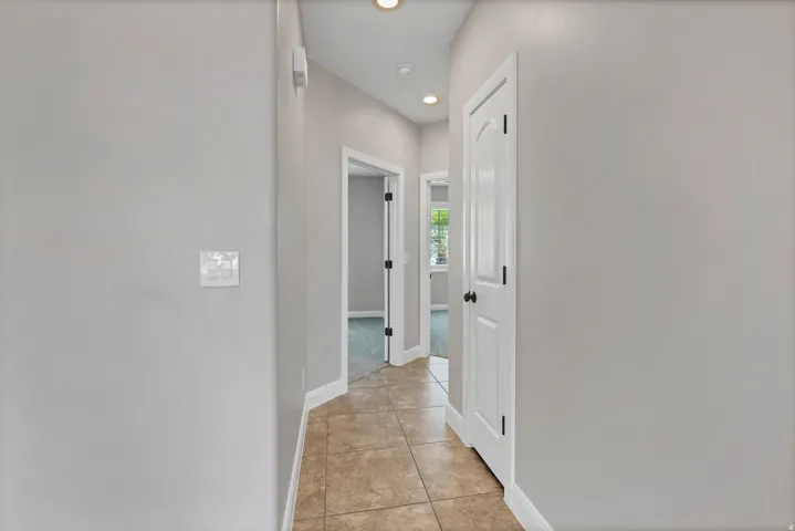 Hallway featuring recessed lighting, tile flooring, and white paneled doors with dark hardware