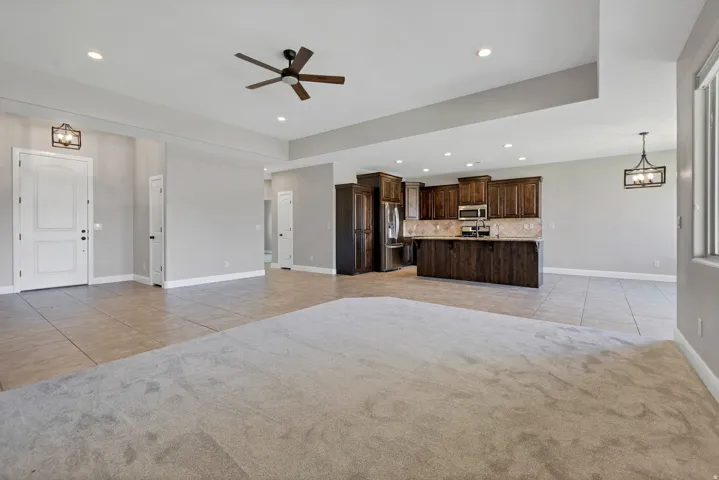 Open-concept living area with mixed flooring, dark wood cabinetry, stainless steel appliances, and recessed lighting