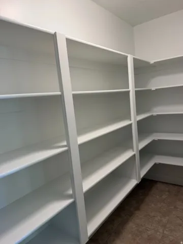 Built-in shelving with multiple levels, white finishes, and a corner configuration